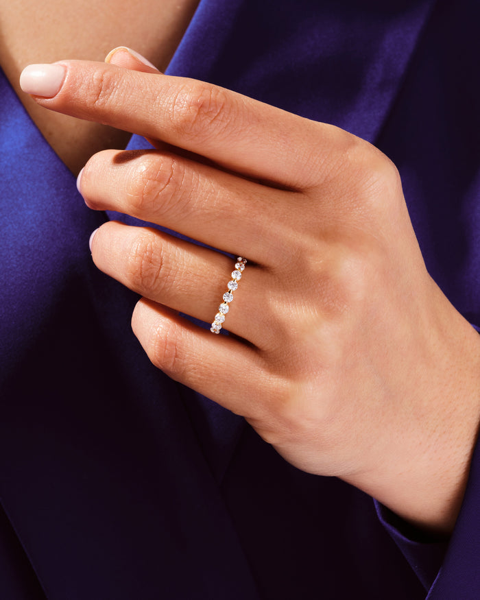 Floating moissanite anniversary band worn on a hand against blue fabric