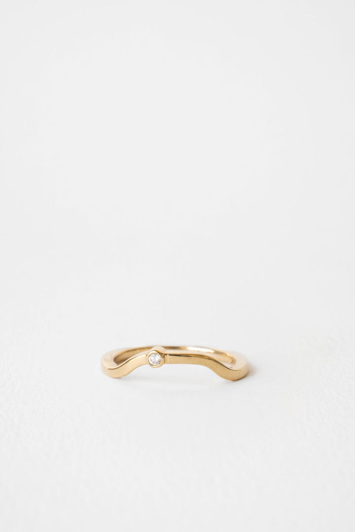 Curved wedding band with a single round moissanite