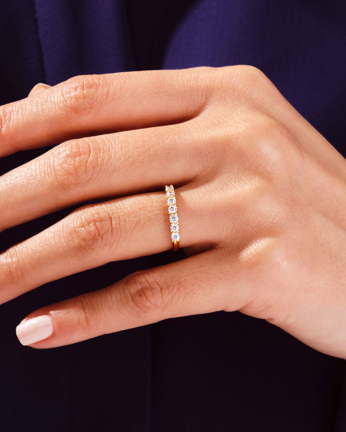 Seven stone moissanite anniversary band in yellow gold worn on a hand