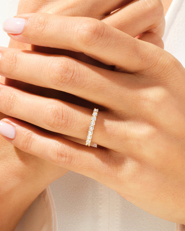 Nine stone moissanite anniversary band in yellow gold worn on a hand