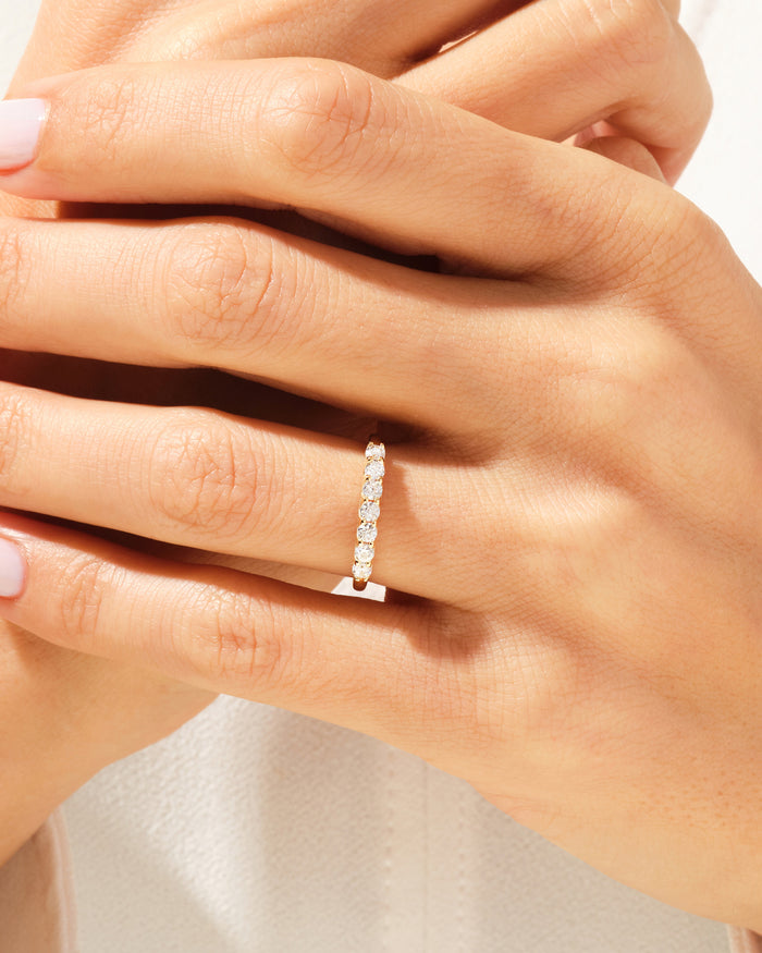 Seven stone moissanite trellis band in yellow gold worn on a hand