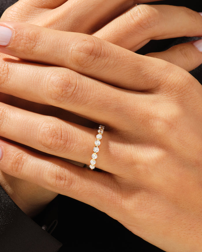 Floating eleven stone moissanite band in yellow gold worn on a hand