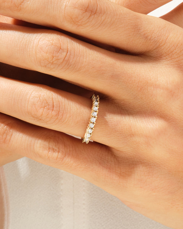 Eleven stone moissanite basket band in yellow gold worn on a hand