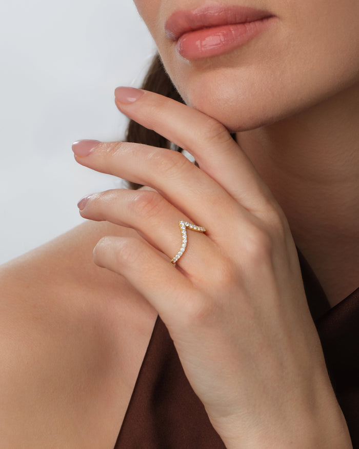 Long curved moissanite wedding band worn on the finger, yellow gold