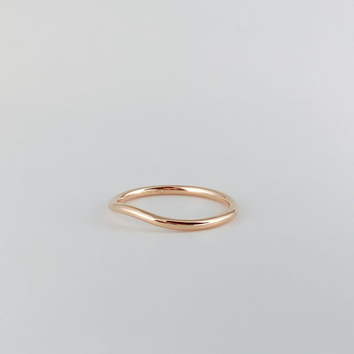 Plain curved wedding band in rose gold, angled view