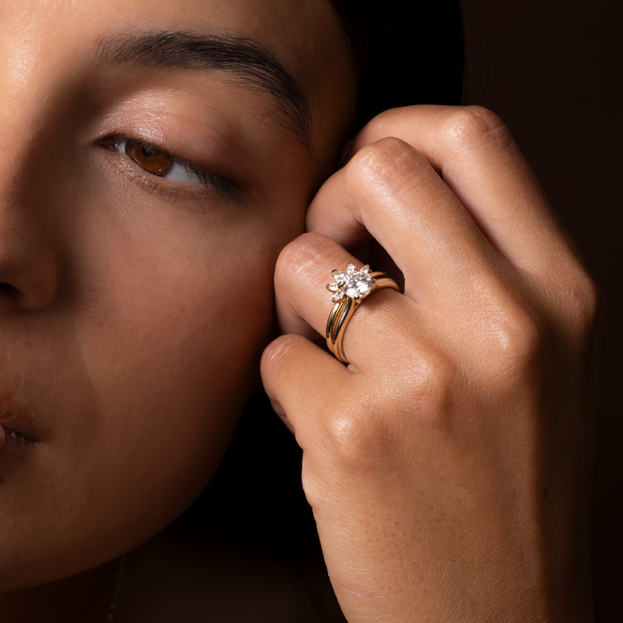 Marquise moissanite curved cluster band worn on a hand beside a round solitaire engagement ring