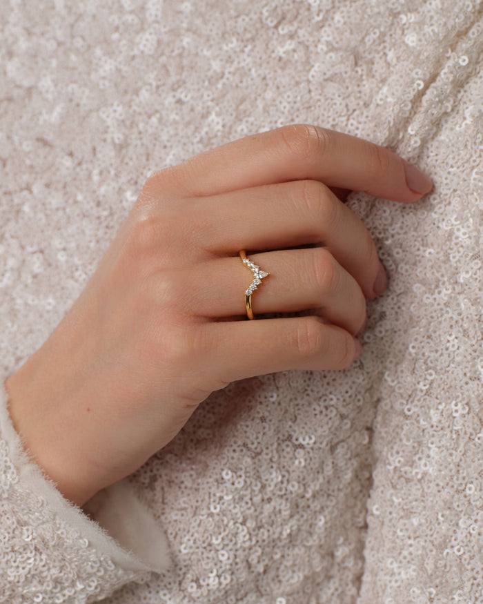 V-shaped moissanite crown wedding band worn on a model's hand