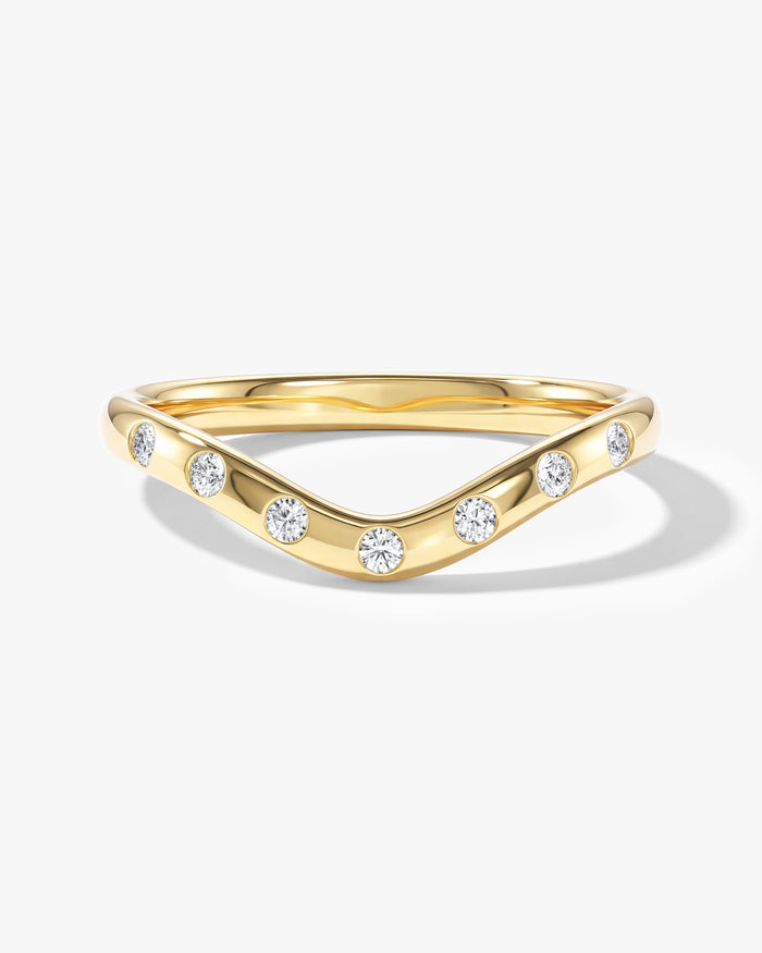 Round moissanite flush set curved wedding band in yellow gold