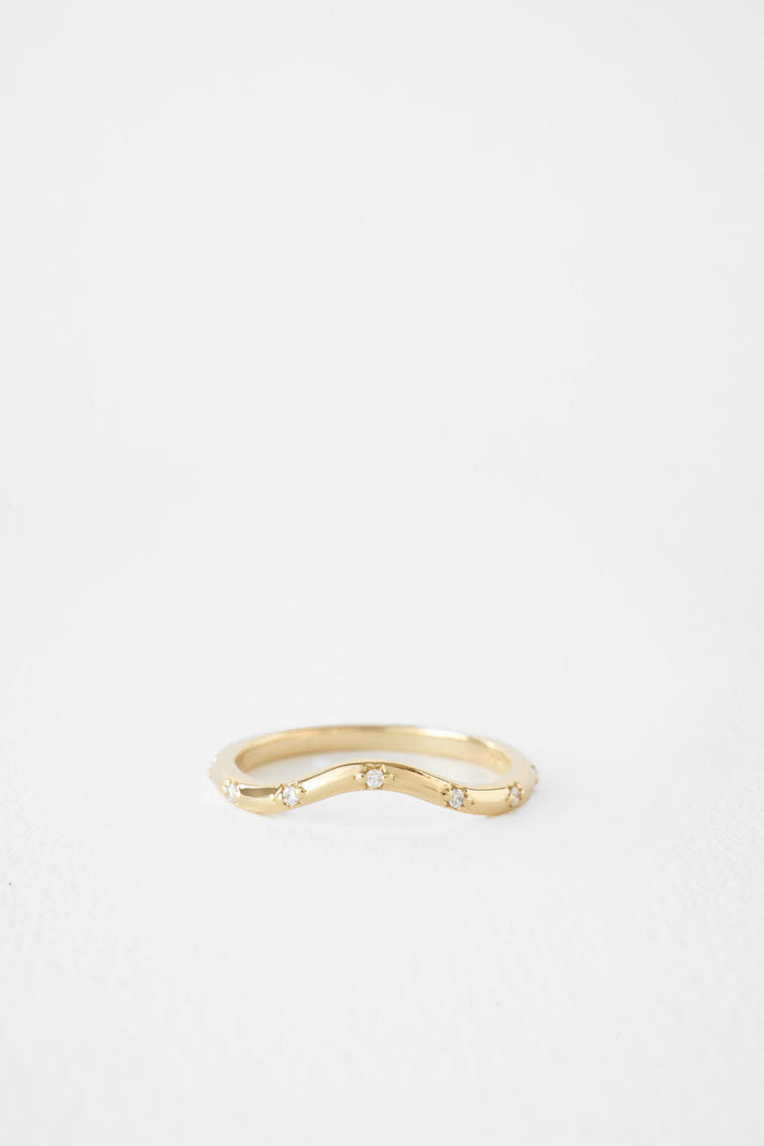 Round moissanite curved flush set wedding band in yellow gold, front view