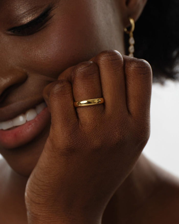 4mm polished dome wedding band in yellow gold worn on a hand