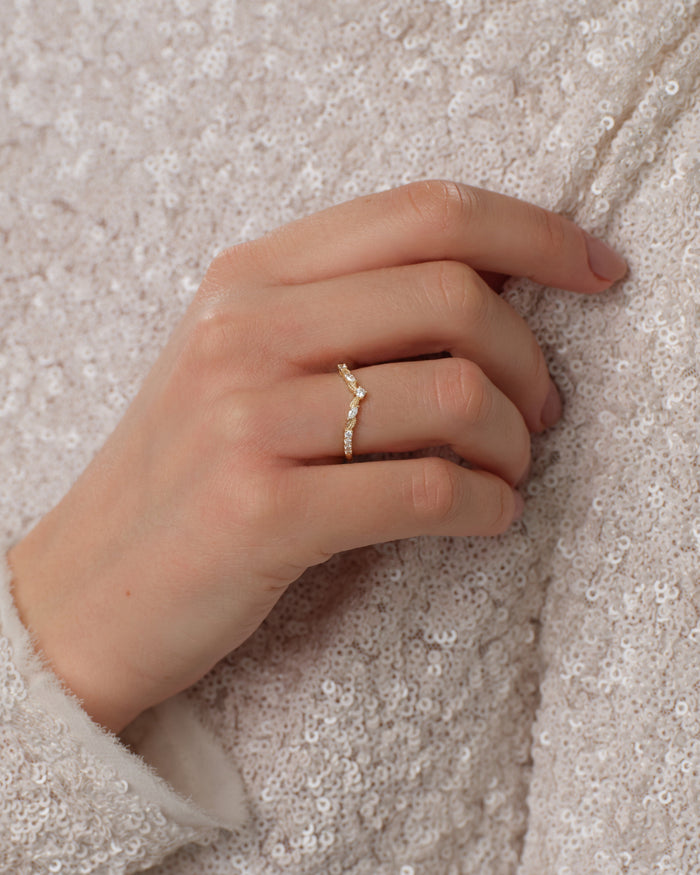 Petal nesting wedding band worn on a hand against a sequin top