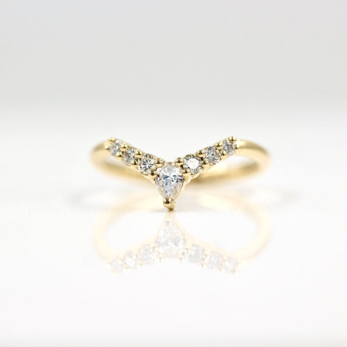 Round and pear moissanite curved V wedding band in yellow gold, front view