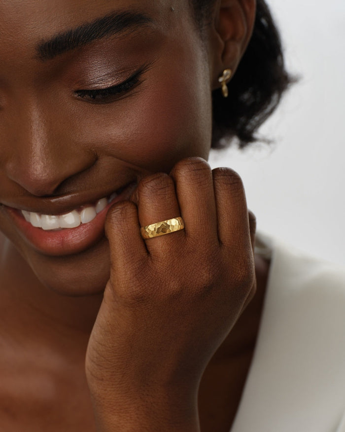 6mm hammered dome gold wedding band worn on a hand held at the cheek