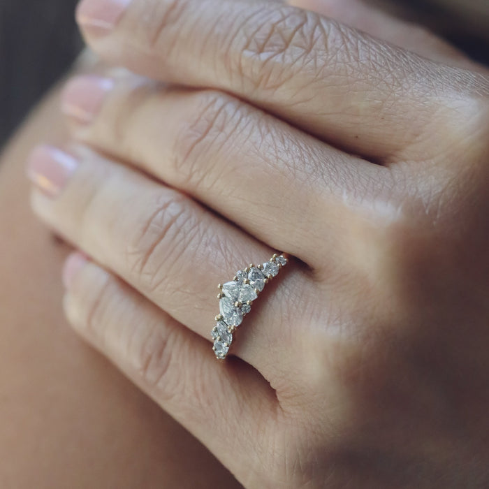 Mixed shape moissanite cluster wedding band in yellow gold worn on a hand