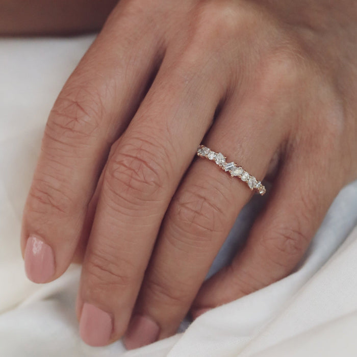 Mixed shape moissanite cluster wedding band in rose gold worn on a finger