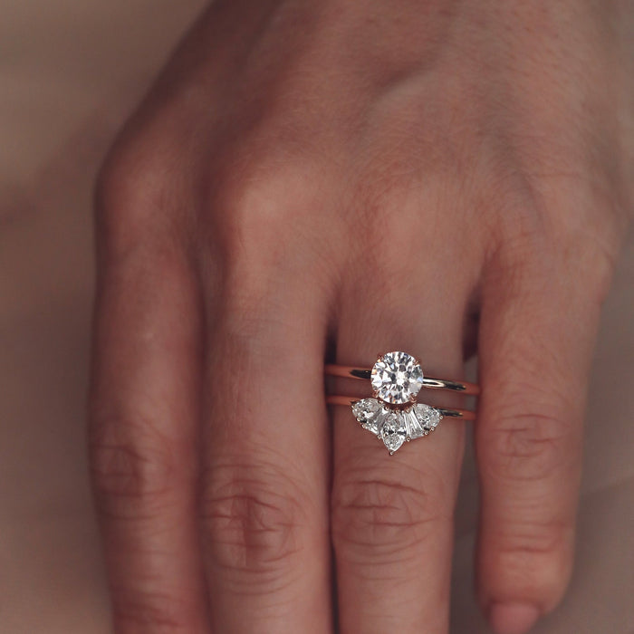 moissanite five stone crown wedding band in rose gold stacked under a round stone solitaire ring
