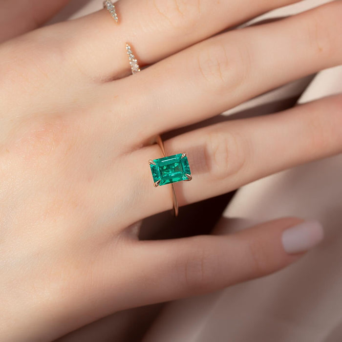 Vivid green emerald cut lab grown emerald in a four claw setting