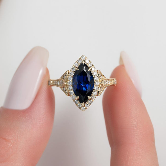 Marquise cut lab grown blue sapphire ring with diamond halo in yellow gold, front view