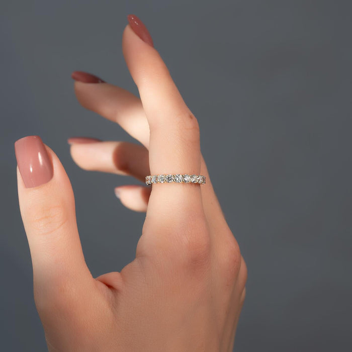 Round moissanite shared prong eternity band on finger