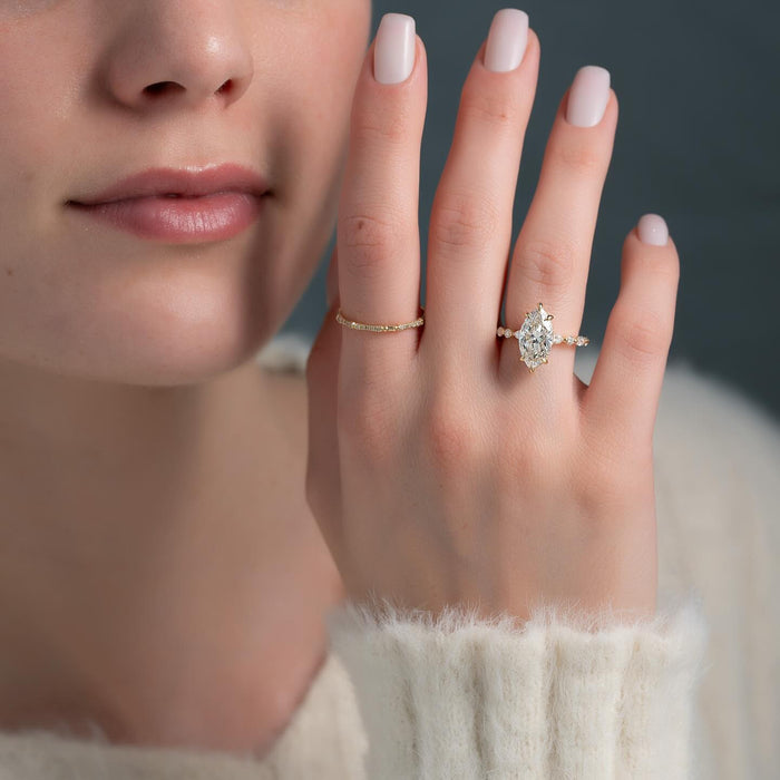 Marquise moissanite hidden halo ring with spaced accent band worn on hand