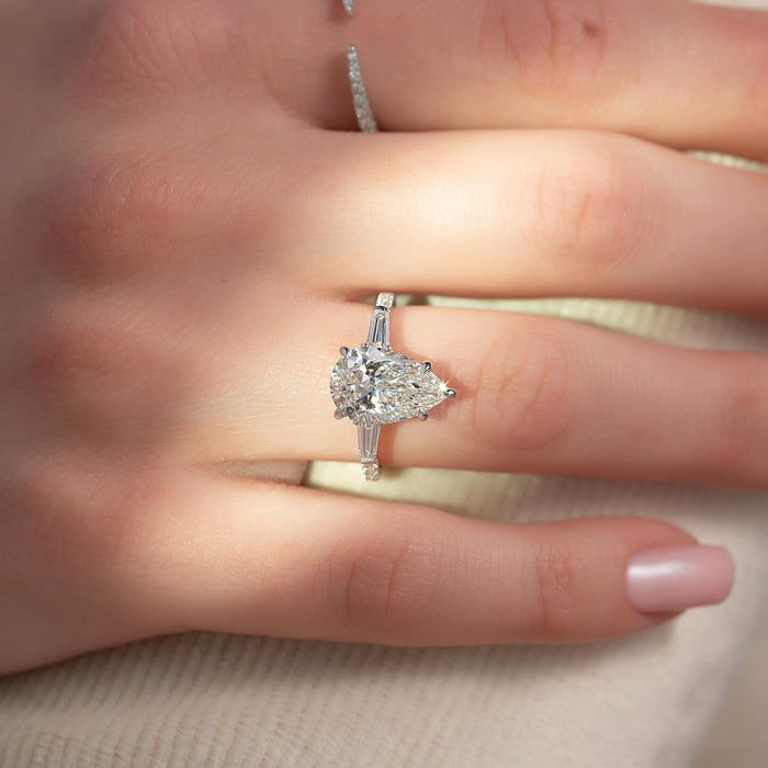 East west pear cut lab grown diamond ring with tapered baguette sides in white gold worn on the hand