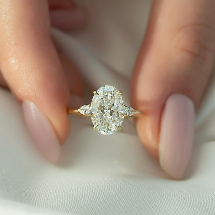 Oval cut lab grown diamond three stone ring with pear side stones in yellow gold