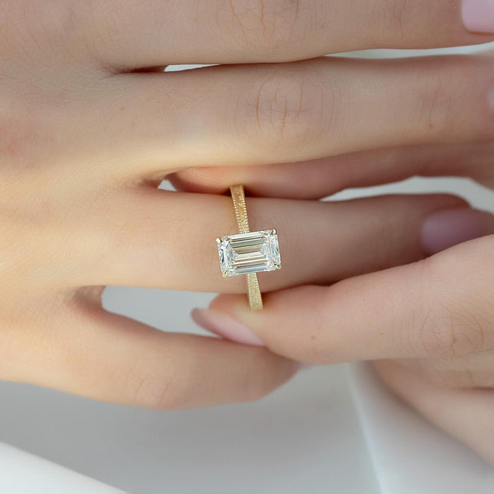 East west emerald cut lab grown diamond ring on a hand engraved milgrain yellow gold band