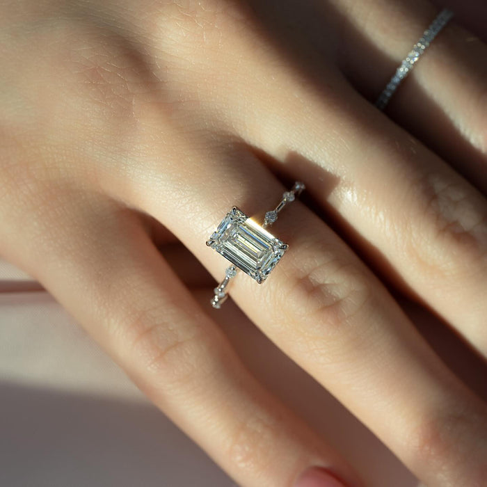 Emerald cut diamond engagement ring with spaced accents worn on the hand