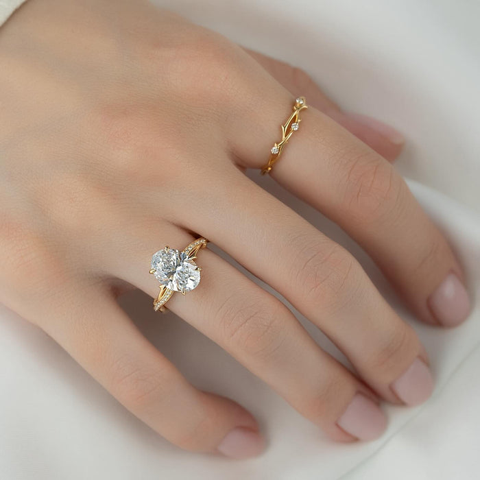 Oval lab grown diamond ring on a pave branch band in yellow gold worn on hand