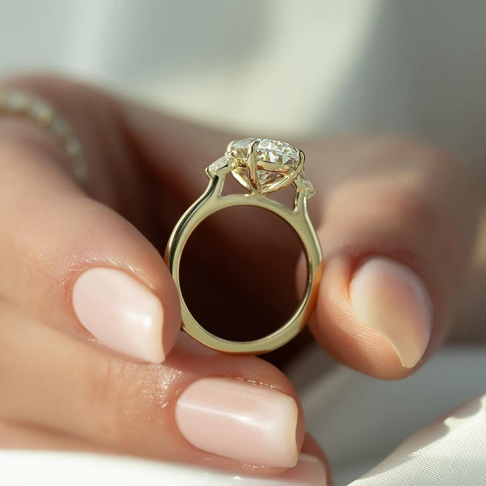 Pear cut side stones facing inward toward the oval diamond