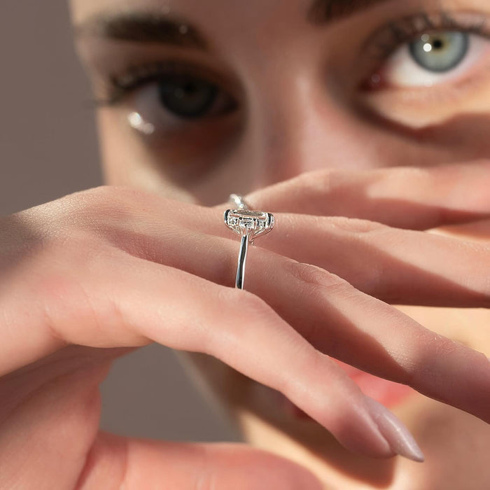 Trapezoid side diamonds set flush against the emerald cut centre stone