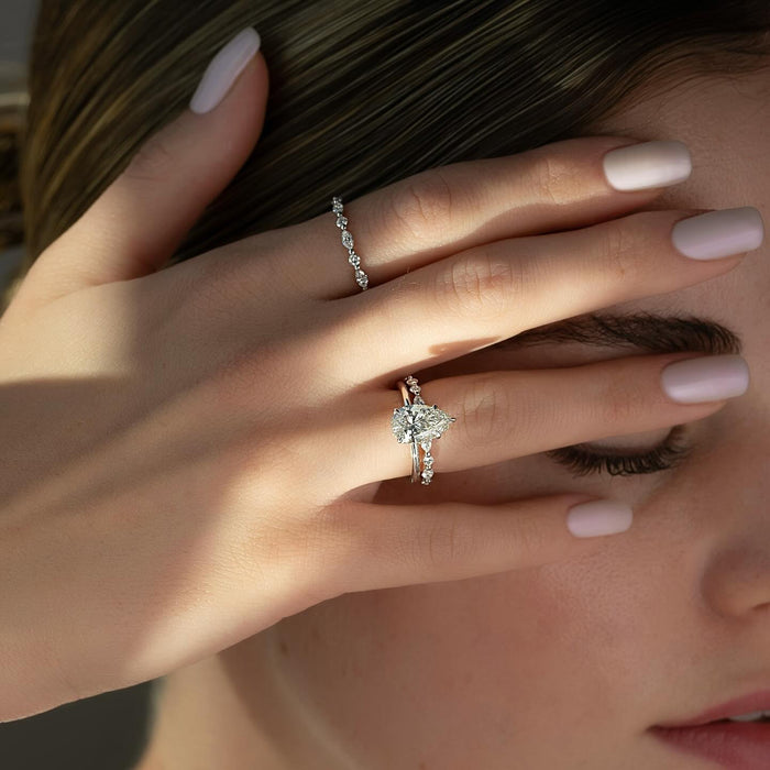 Pear diamond engagement ring worn on hand with spaced accents