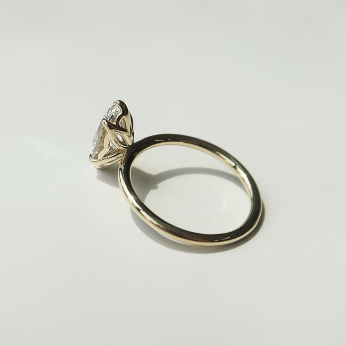 Profile of the marquise lab grown diamond solitaire showing the low setting and round wire band