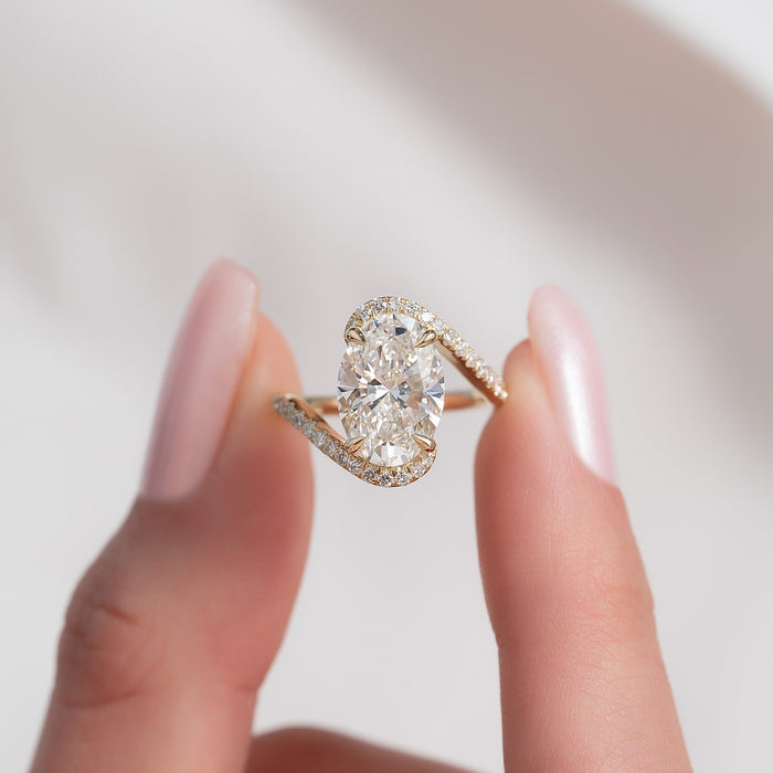 Oval cut lab grown diamond bypass ring with curved pave arms in yellow gold