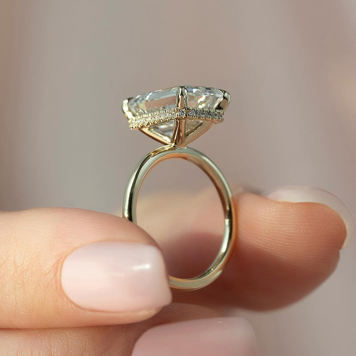 Concealed halo pave around the basket of the emerald cut diamond