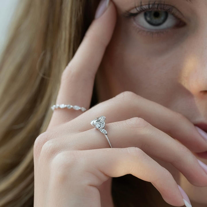 Oval lab grown diamond ring with marquise and pear accents worn on the hand