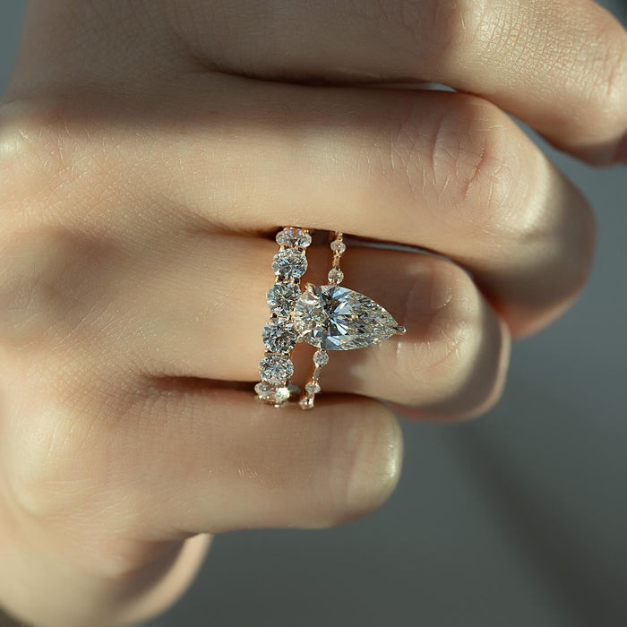 Pear engagement ring and matching diamond band worn together on the same finger