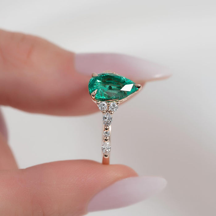 Angled view showing the vivid green pear emerald and marquise diamond accents