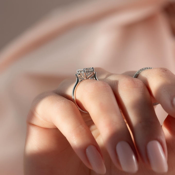 Round accent diamonds set at each corner of the emerald cut centre stone