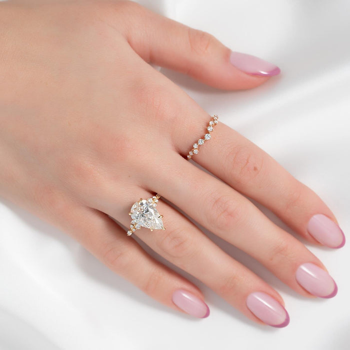 Pear cut lab grown diamond engagement ring worn on the hand with a scattered diamond band