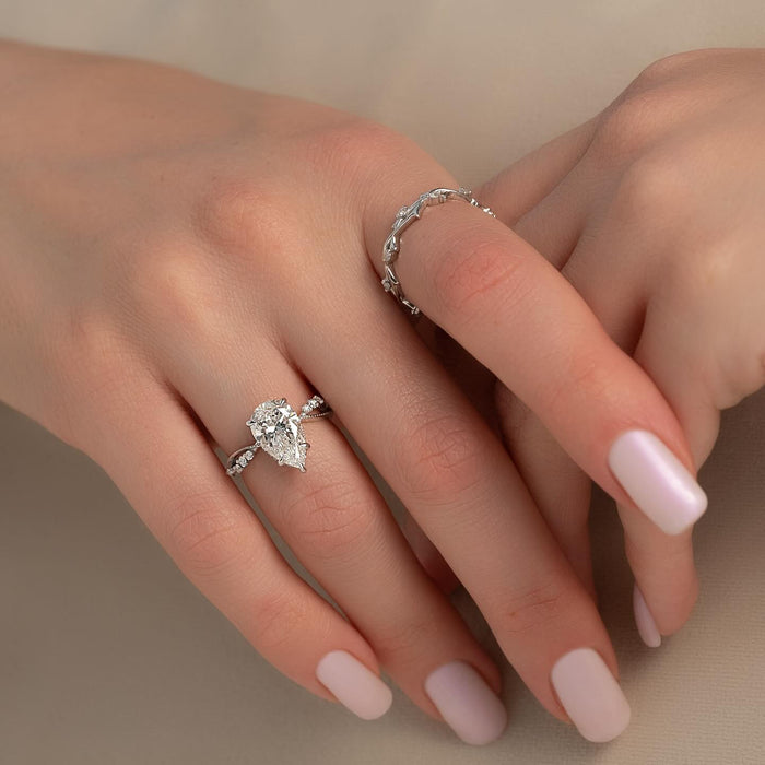 Leaf shaped accents set against the shoulders of the pear diamond