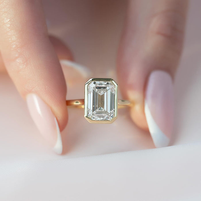 Emerald cut lab grown diamond ring in a full yellow gold rub over bezel on a slim band