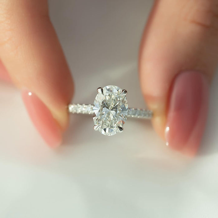 Oval diamond in a four claw setting above a pave band