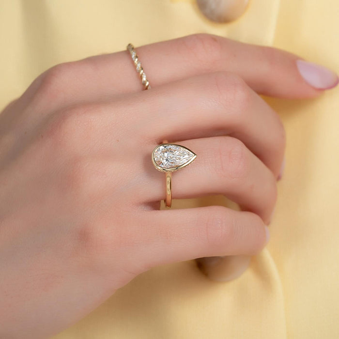 Bezel set pear cut lab grown diamond engagement ring worn on the hand