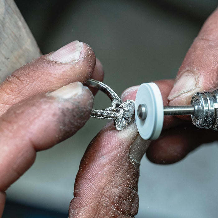 A goldsmith finishing the engraved oval diamond ring by hand in our Surat workshop