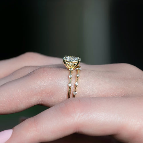 Cushion cut lab grown diamond engagement ring stacked with a matching spaced accent wedding band in yellow gold