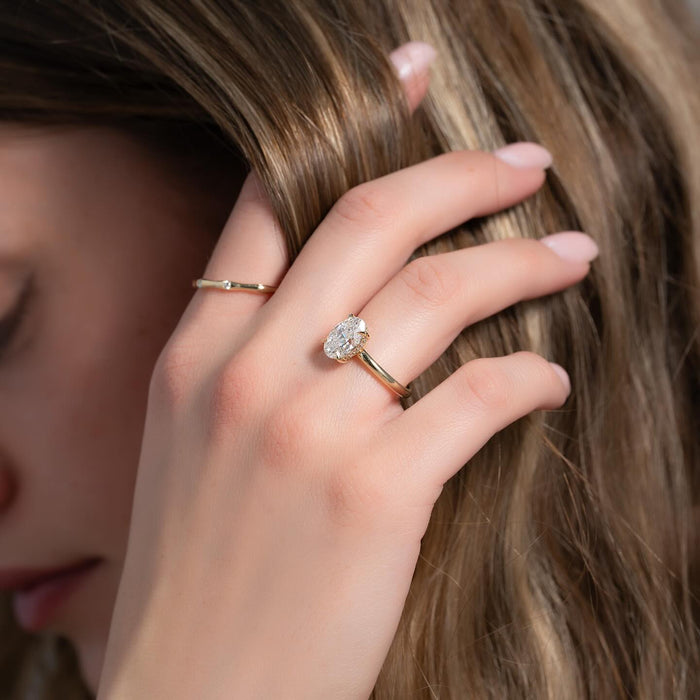 Oval cut lab grown diamond ring with pave hidden halo in yellow gold worn on the hand
