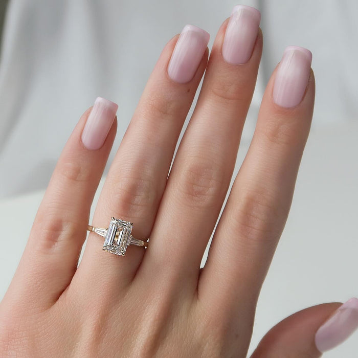 Emerald cut lab grown diamond ring with baguette sides worn on the hand