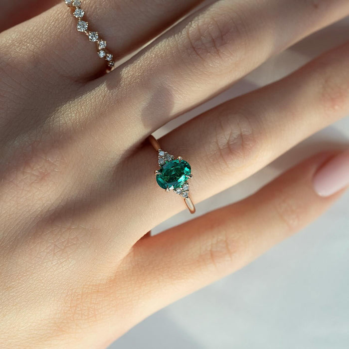 Oval emerald engagement ring in rose gold worn on the hand