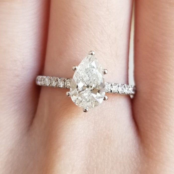Pear solitaire with pave shoulders on the finger